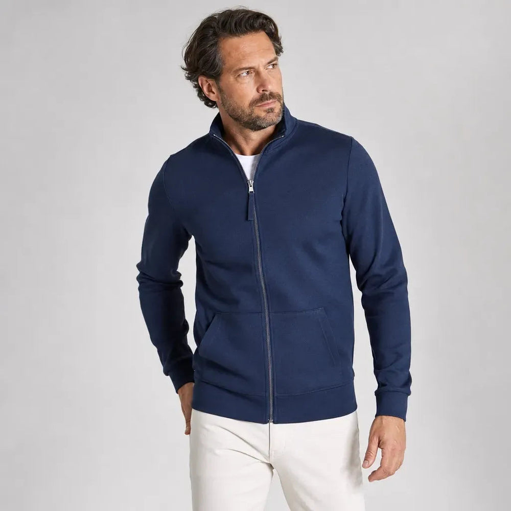 Man in een marineblauw sweatvest over een wit T-shirt, met een lichte broek | Boutique Moda