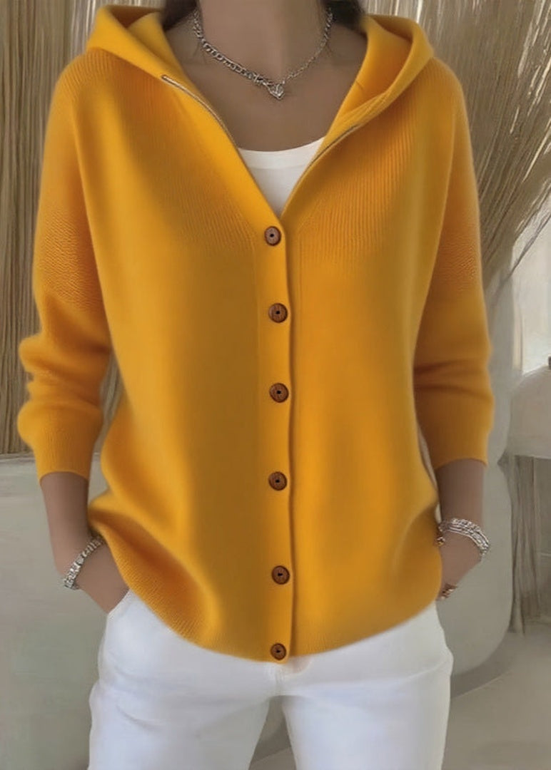 Gele capuchonvest met knoopsluiting, gedragen door vrouw, met witte broek | Boutique Moda