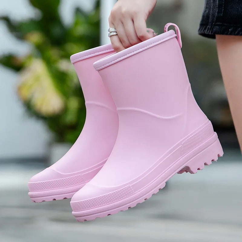 Korte rubberen laarzen, mat in roze, in de hand gehouden