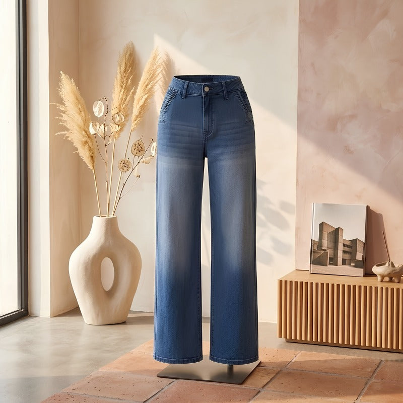 Vintage jeans voor dames in blauw met wijde pijpen, productfoto op een standaard, warm interieur met droogbloemen