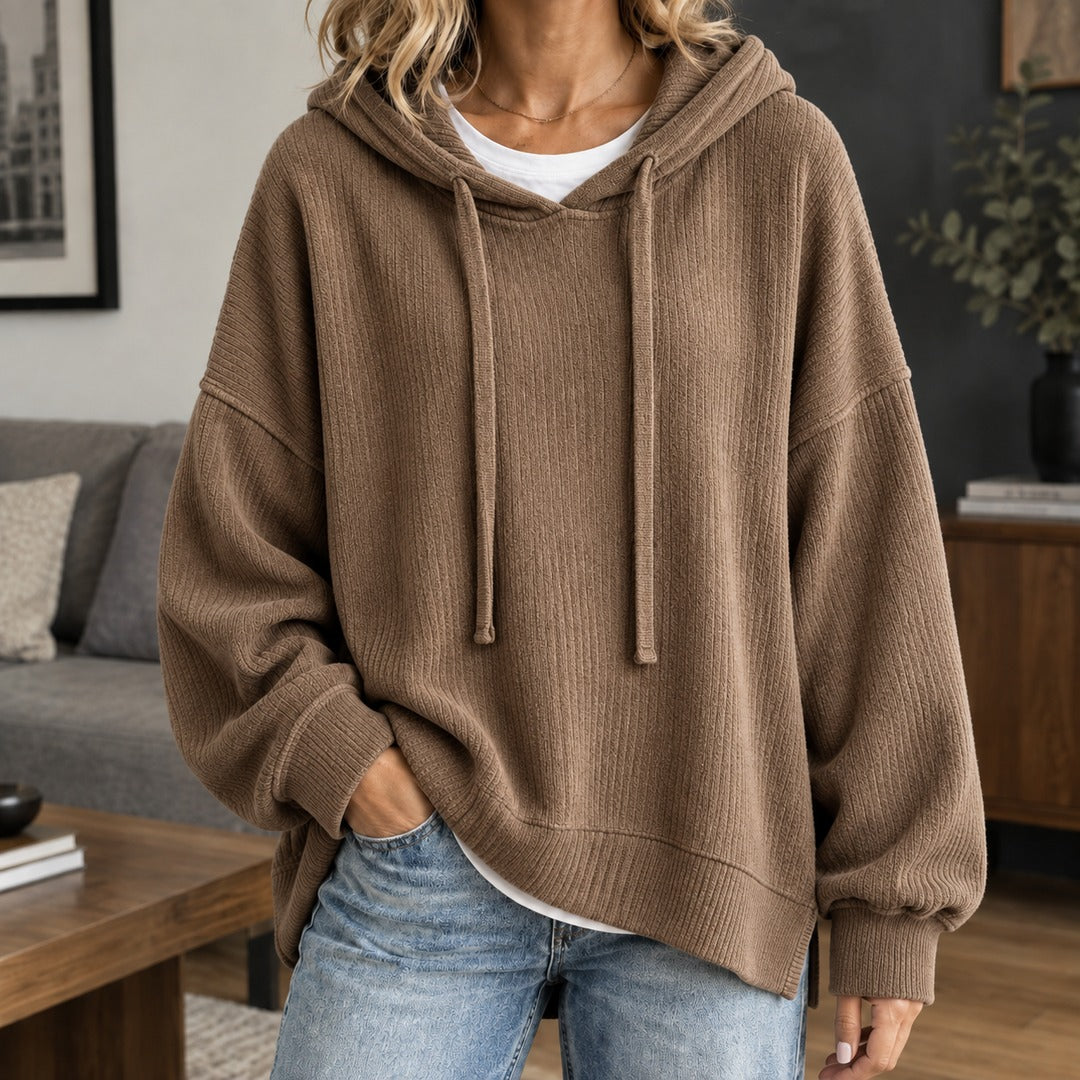 Vrouw in een bruine gebreide trui over een wit T-shirt, met een jeans | Boutique Moda