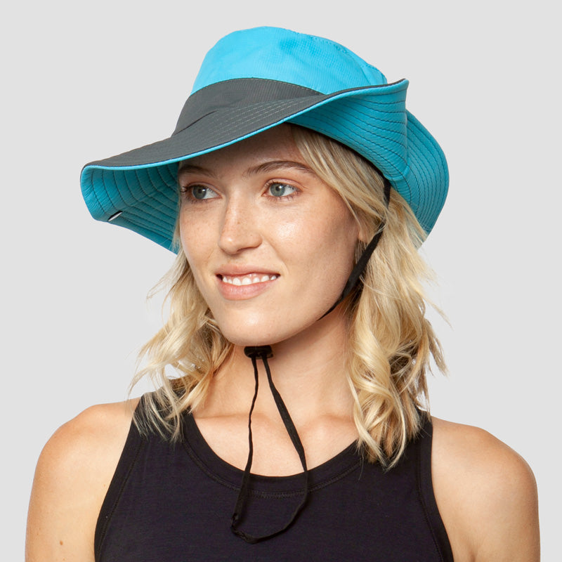 Blauwgrijze brede-rand zonnehoed met kinband, gedragen door glimlachende jonge vrouw | Boutique Moda