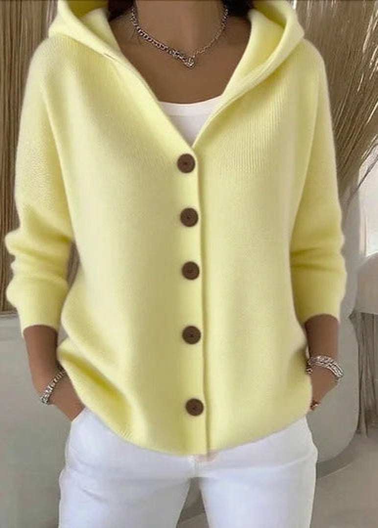 Geel gebreid capuchonvest met knoopsluiting, gedragen door vrouw met witte broek | Boutique Moda
