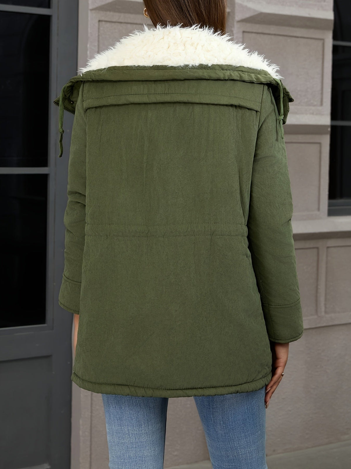 Achterkant van de olijfgroene parka op een jeans