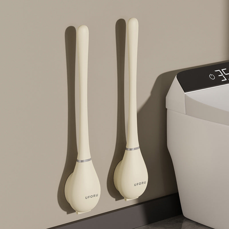 Twee crèmekleurige siliconen wc-borstels wandgemonteerd naast toilet in badkamer | Boutique Moda