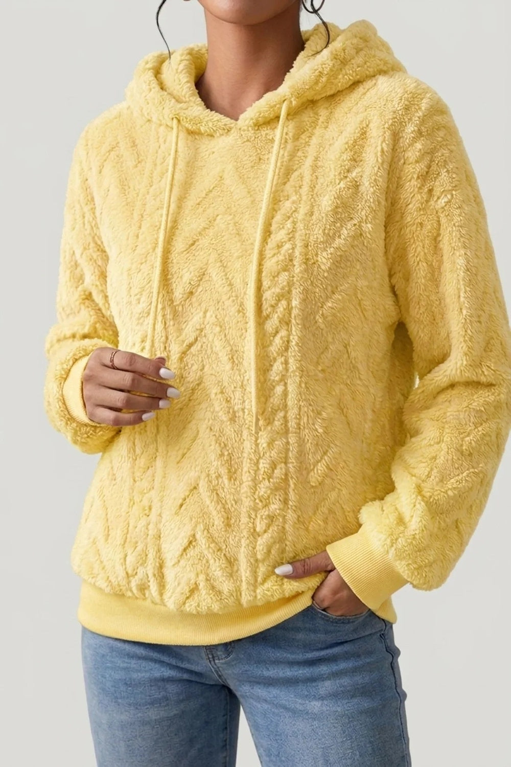 Vrouw in een gele teddytrui met kabelpatroon, hand in de broekzak | Boutique Moda