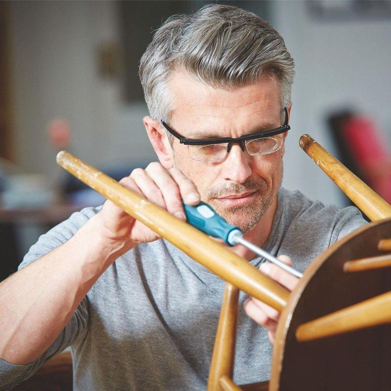 Man met zwarte leesbril repareert houten stoel met schroevendraaier | Boutique Moda