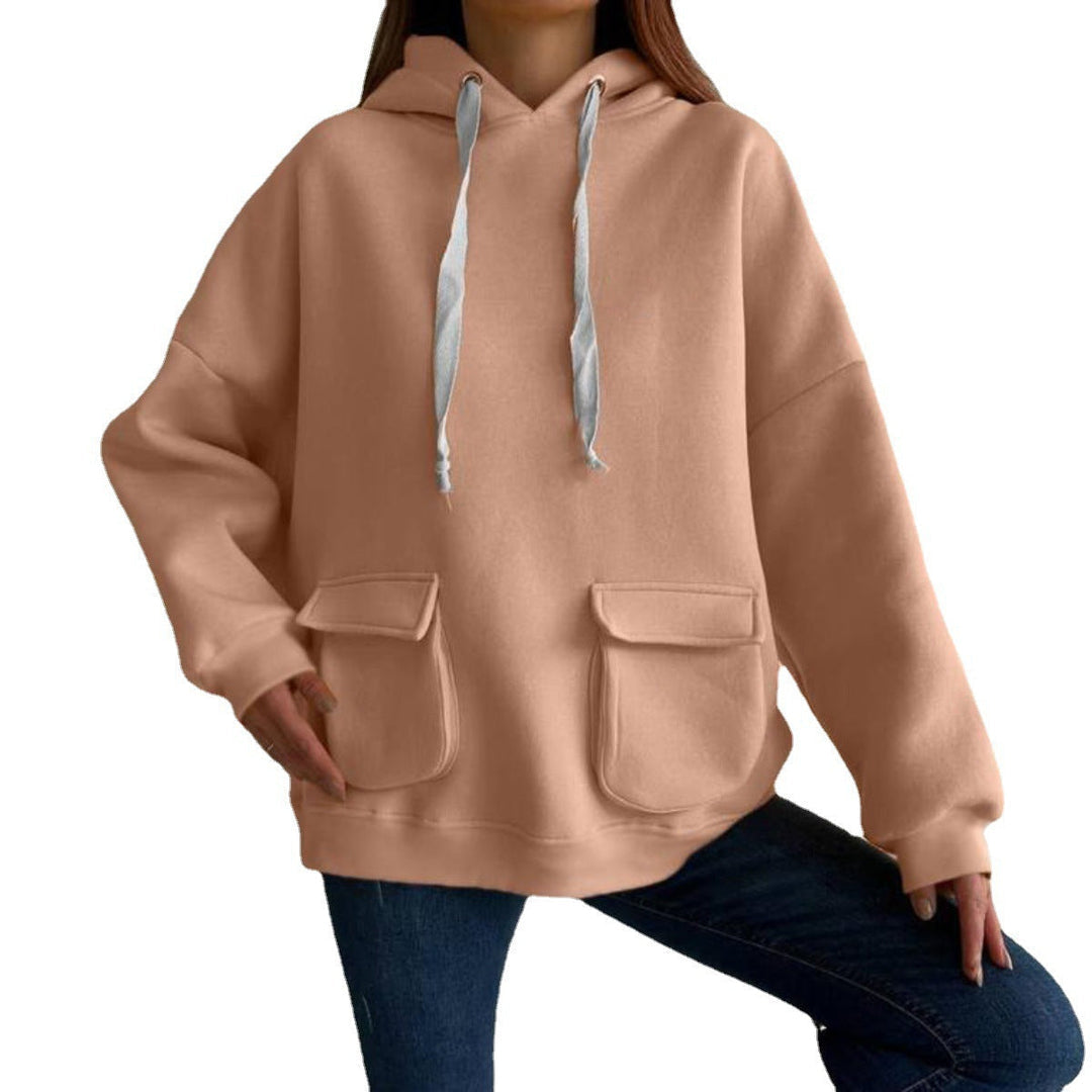 Vrouw in een perzikkleurige oversized hoodie met klepzakken en verlaagde schouders, op een witte achtergrond | Boutique Moda