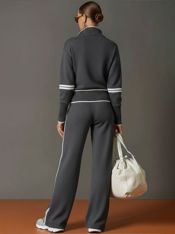 Grijs gebreid trainingspak met witte strepen, gedragen door vrouw met tas | Boutique Moda
