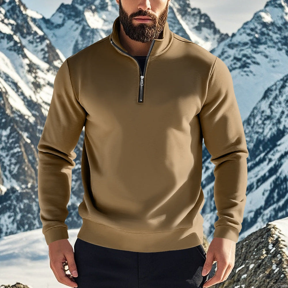 Man in een bruine gevoerde trui met een donkere broek voor besneeuwde toppen | Boutique Moda