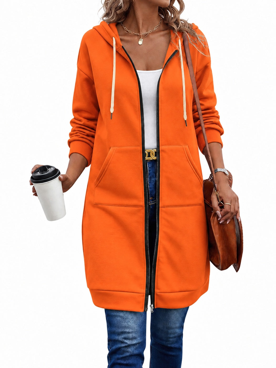 Vrouw in een lang oranje sweatvest, open over een wit topje, met een jeans | Boutique Moda