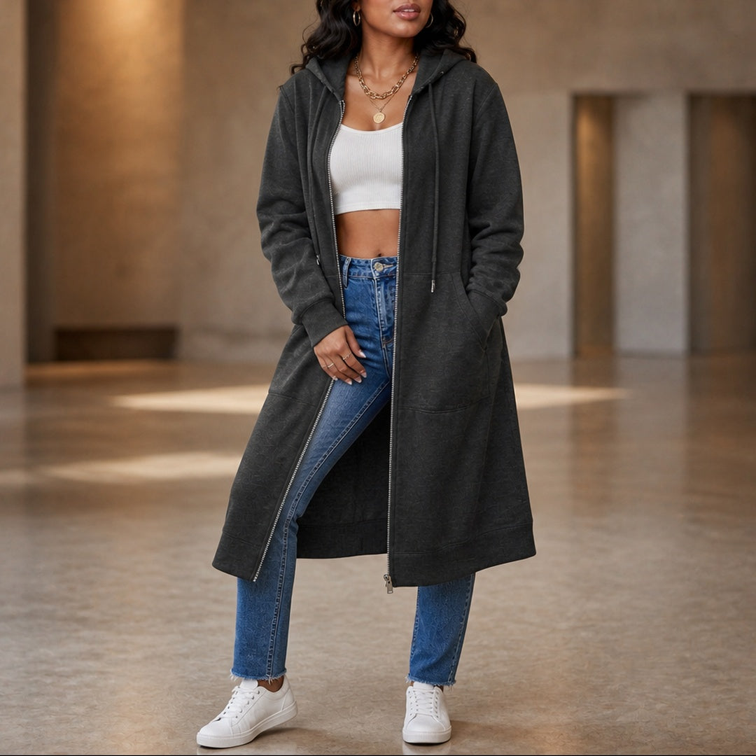 Vrouw ten voeten uit in een open lang antraciet vest met een jeans, hand in de zak | Boutique Moda