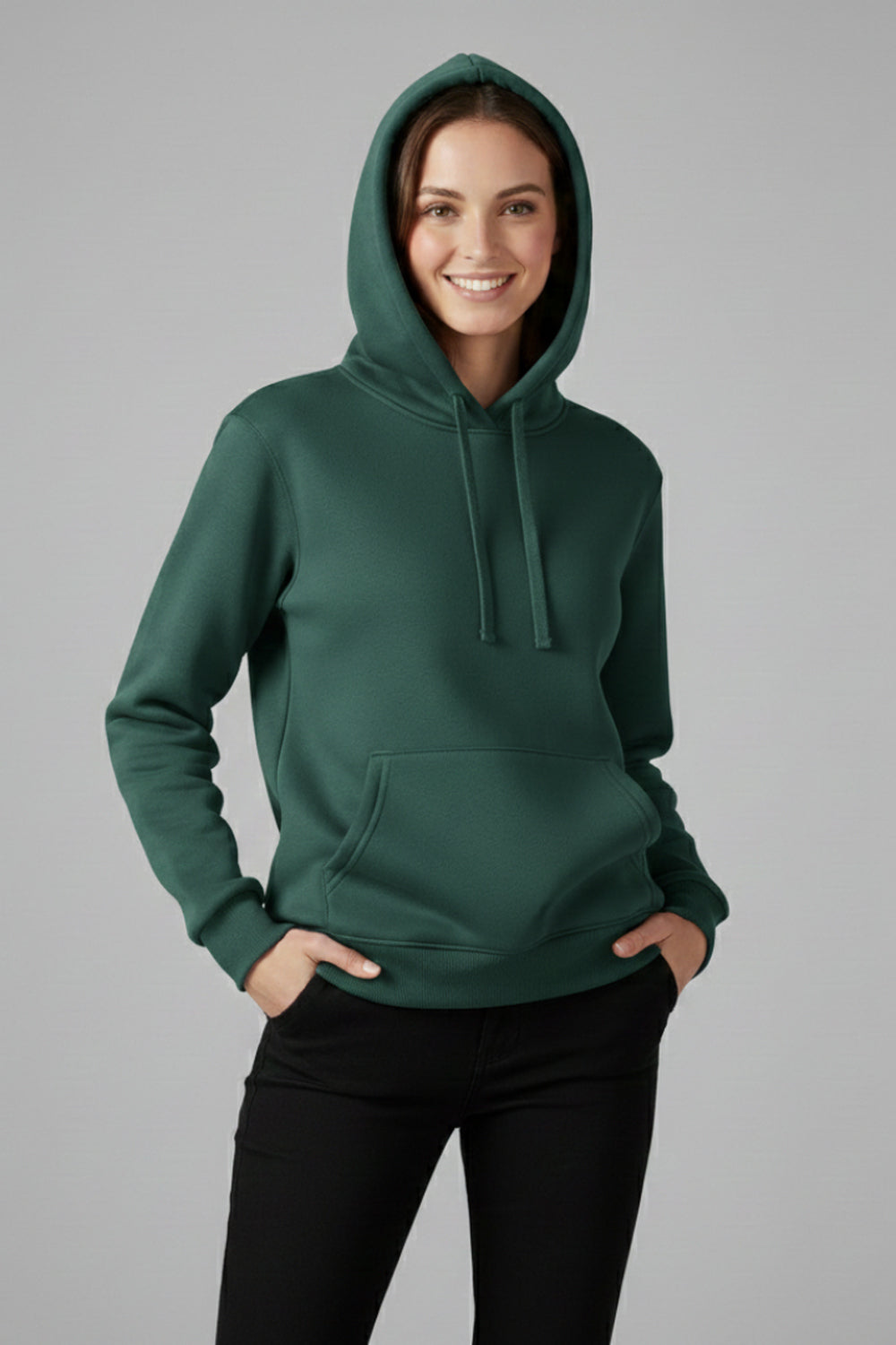 Vrouw in een donkergroene basic hoodie met capuchon en geribde boorden, handen in de broekzakken | Boutique Moda