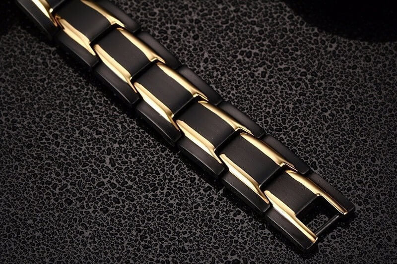 Zwart-gouden roestvrijstalen armband met schakelpatroon, plat neergelegd op donkere ondergrond | Boutique Moda