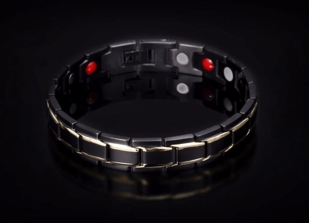 Zwart-gouden metalen armband met vouwsluiting, vrijstaand op reflecterende zwarte achtergrond | Boutique Moda