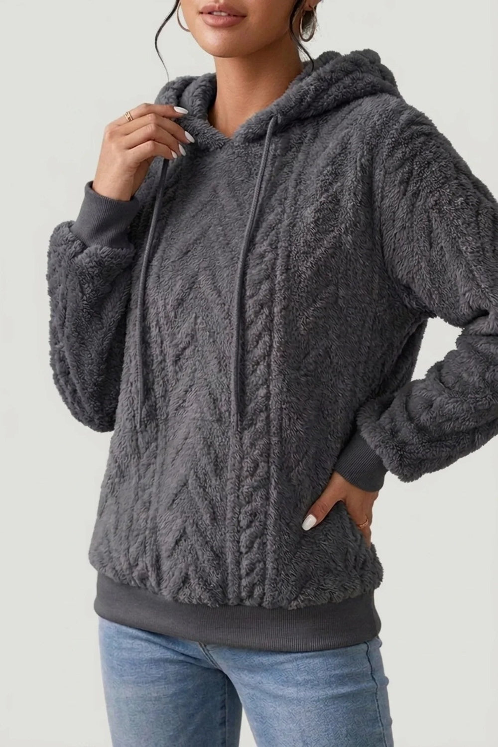 Vrouw in een donkergrijze teddytrui, een hand bij de capuchon, de andere in de zak | Boutique Moda