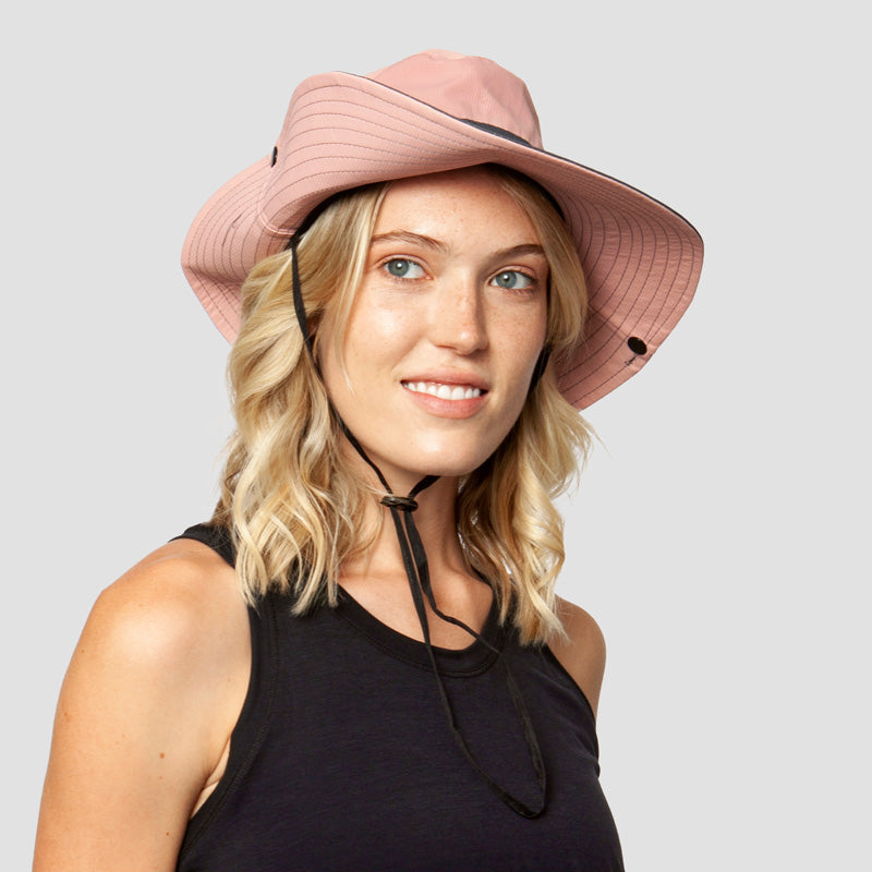 Roze brede-rand zonnehoed met kinband, gedragen door glimlachende vrouw met blond haar | Boutique Moda