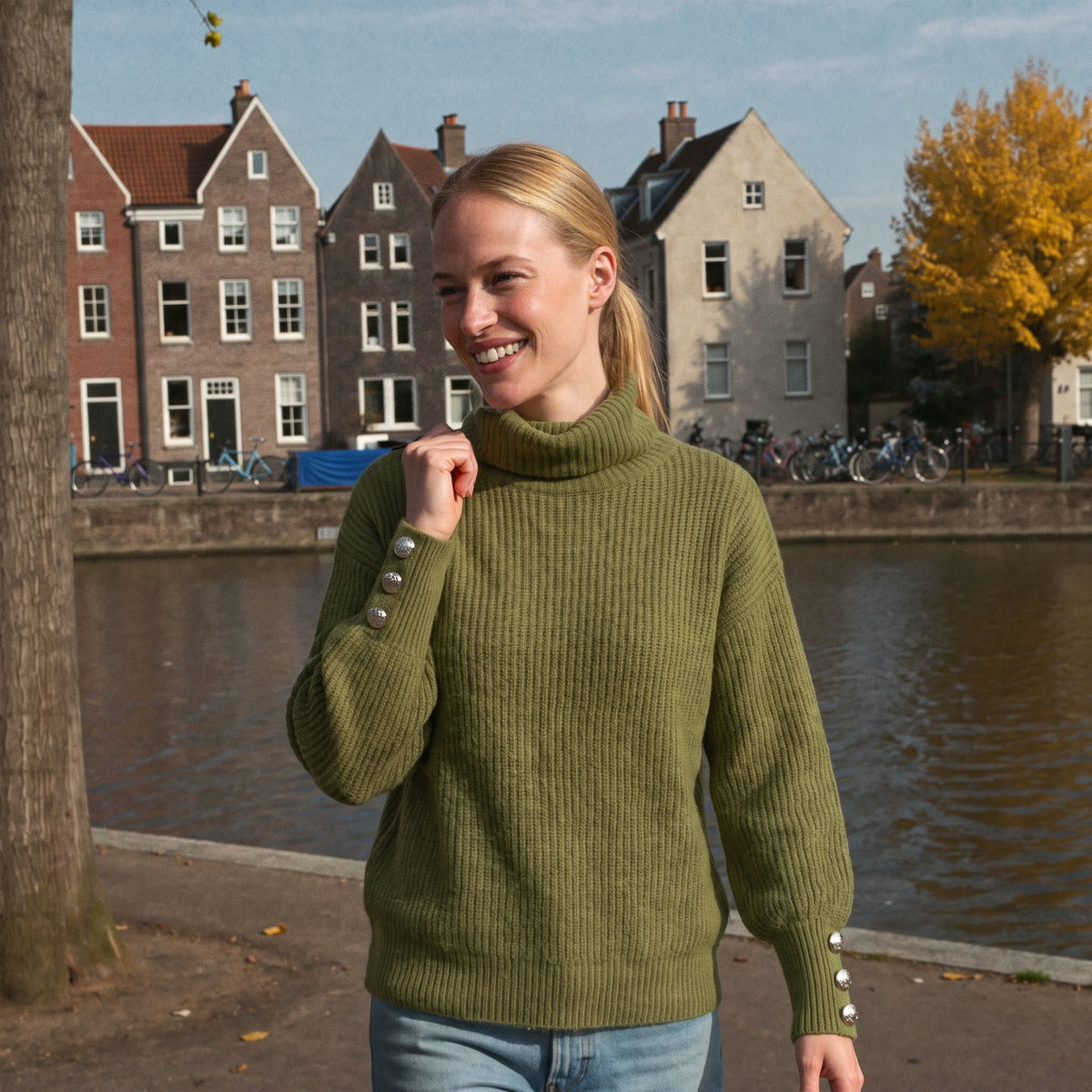 Trui met hoge col en sierknopen in olijfgroen, gedragen langs de Oudegracht in Utrecht