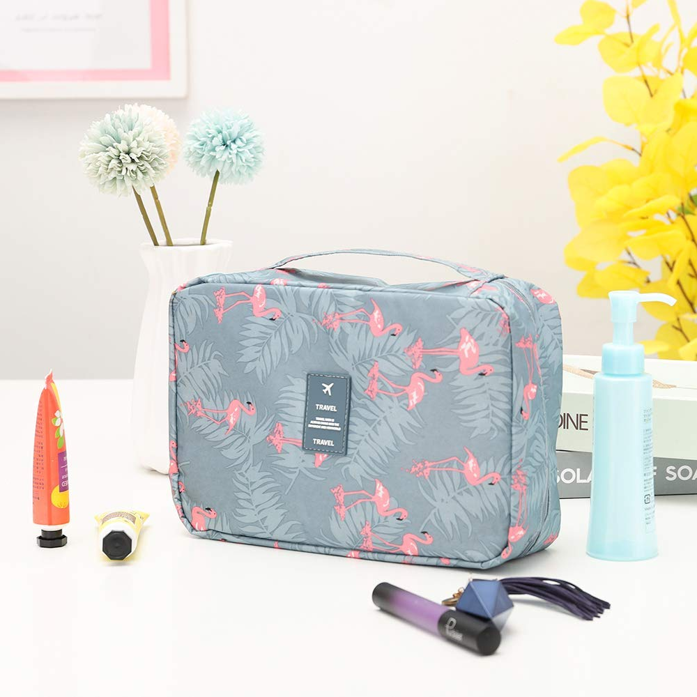 Grijze toilettas met roze flamingoprint, plat neergelegd op witte tafel | Boutique Moda