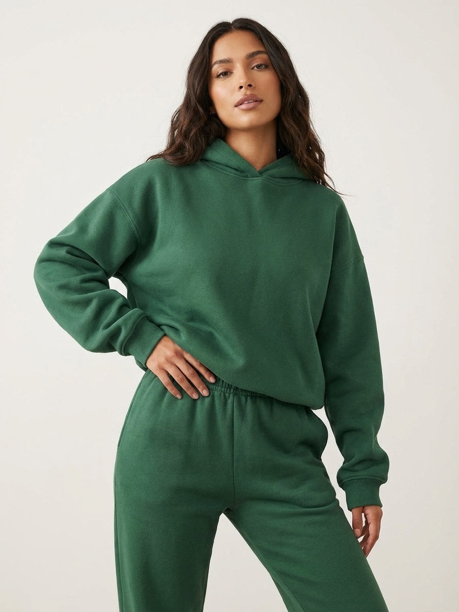 Oversized hoodie en joggingbroek in donkergroen, hand op de heup