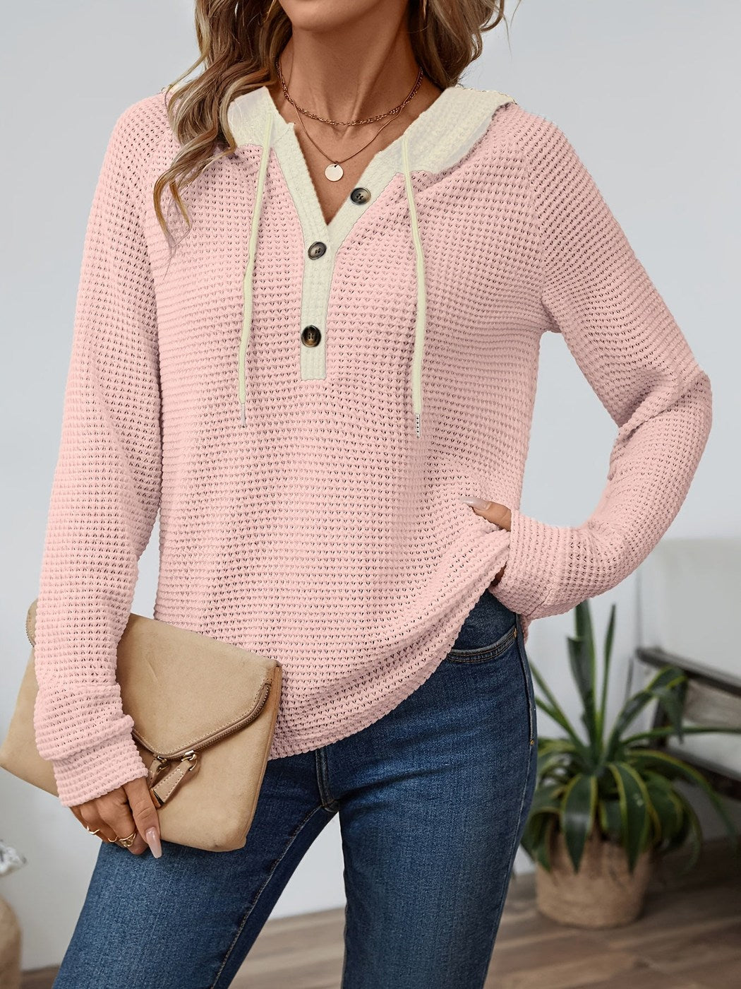Vrouw in een wafelhoodie in Roze/Crème met een clutch, hand op de heup | Boutique Moda