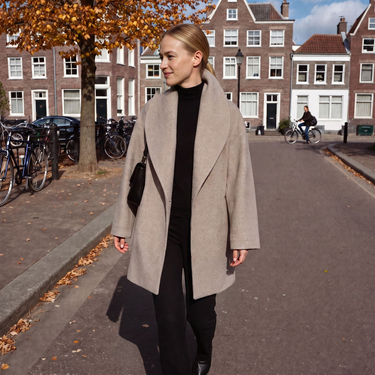 Oversized wollen jas met sjaalkraag voor dames in taupe, gedragen langs een Amsterdamse gracht