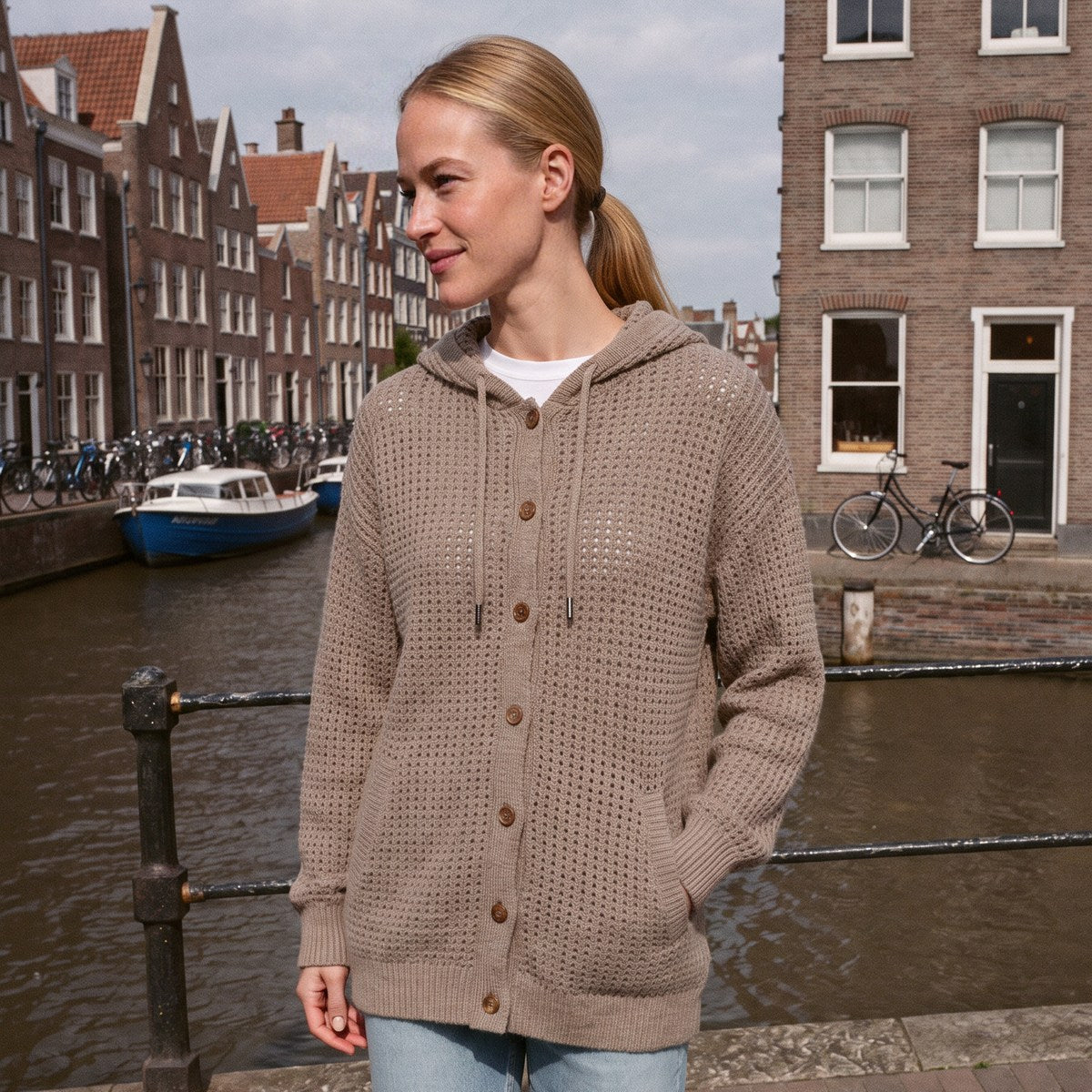 Damesvest met capuchon in taupe, gedragen langs een gracht in Amsterdam