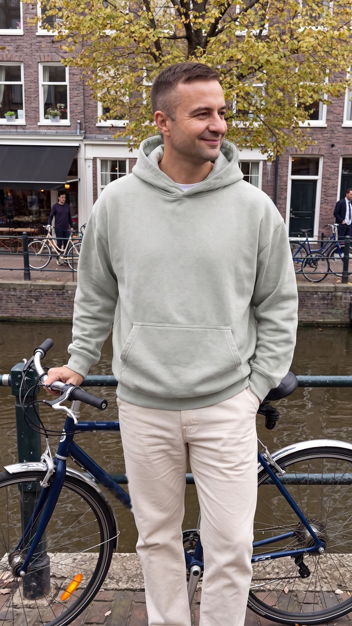 Oversized herenhoodie in saliegroen, gedragen aan een Nederlandse gracht