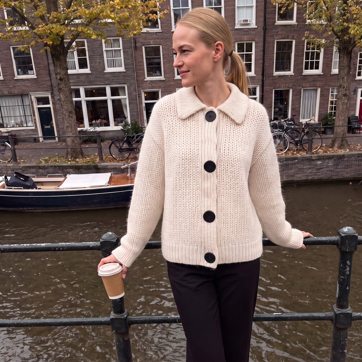 Oversized grof gebreid vest met kraag in gebroken wit, gedragen aan een Nederlandse gracht