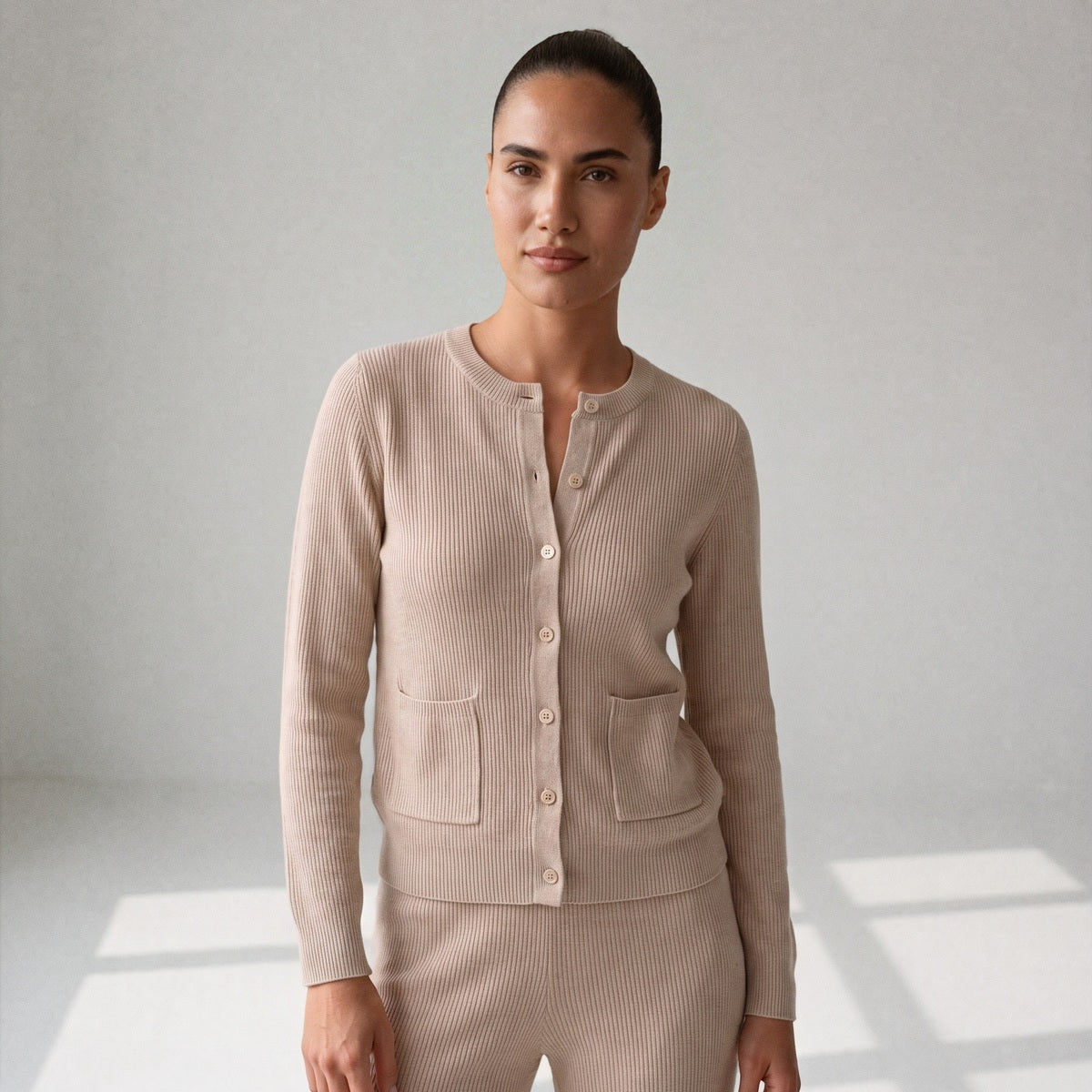 Beige gebreide set, close-up van het vest met knopen aan een model
