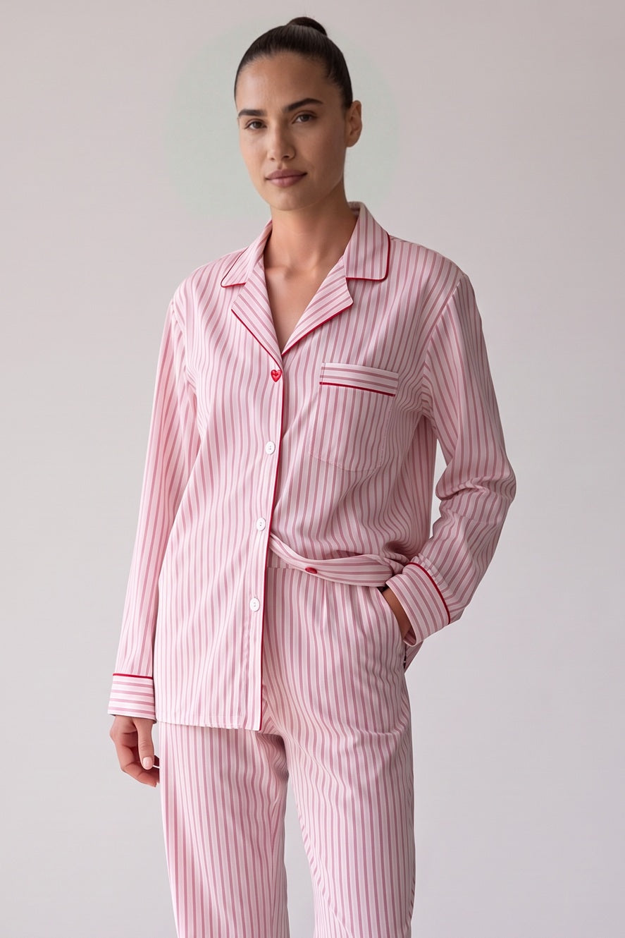 Roze gestreepte pyjamablouse met rode biezen en een rood hartvormig knoopje, close-up