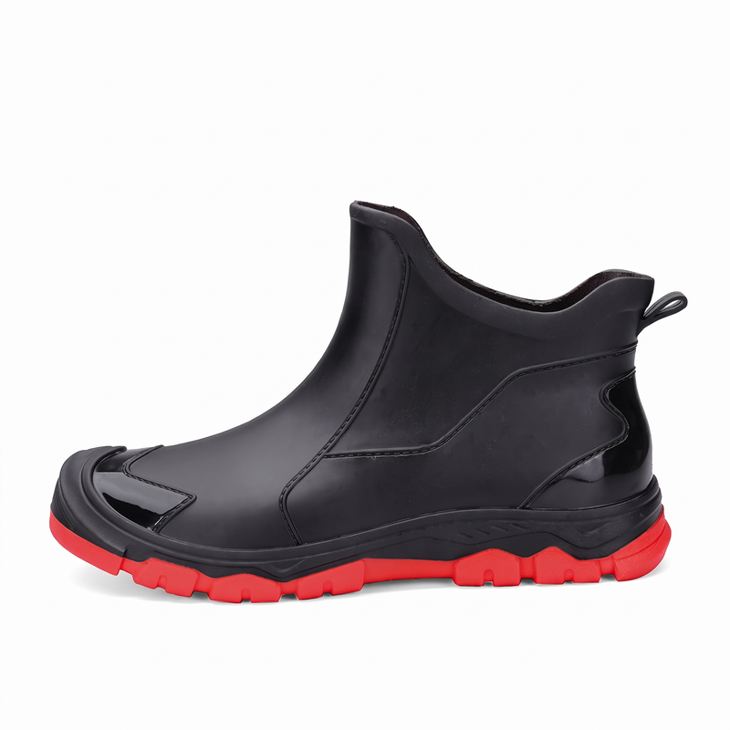 A black ankle rain boot with a red sole and a small patch on the side reading a partial brand name.