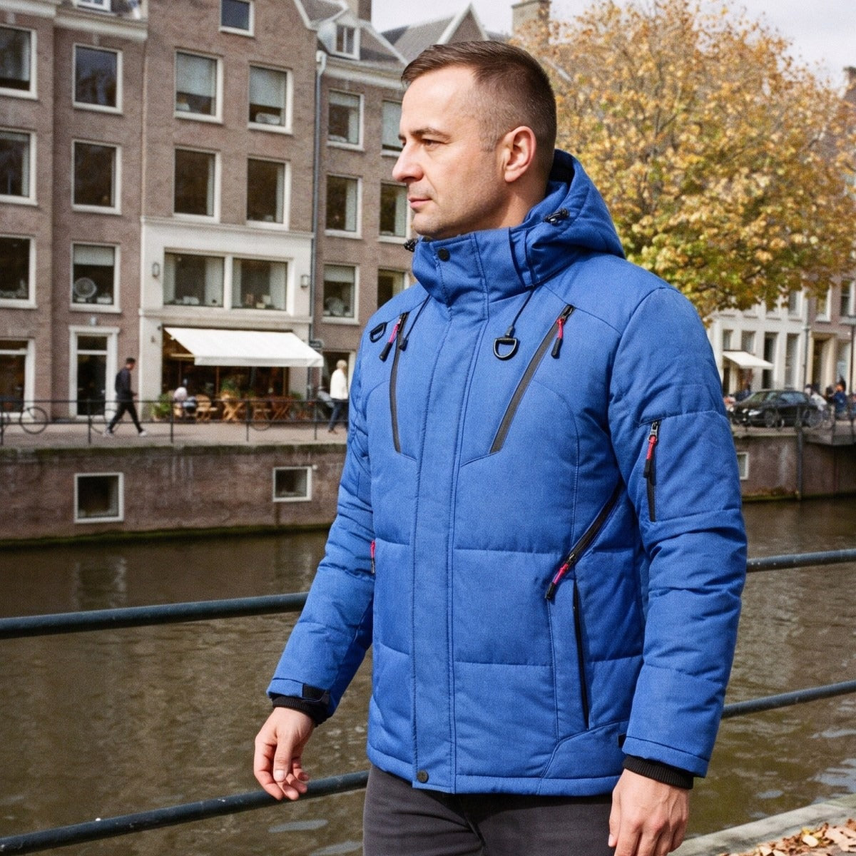 Pufferjas heren in kobaltblauw met capuchon, gedragen langs een gracht in Utrecht