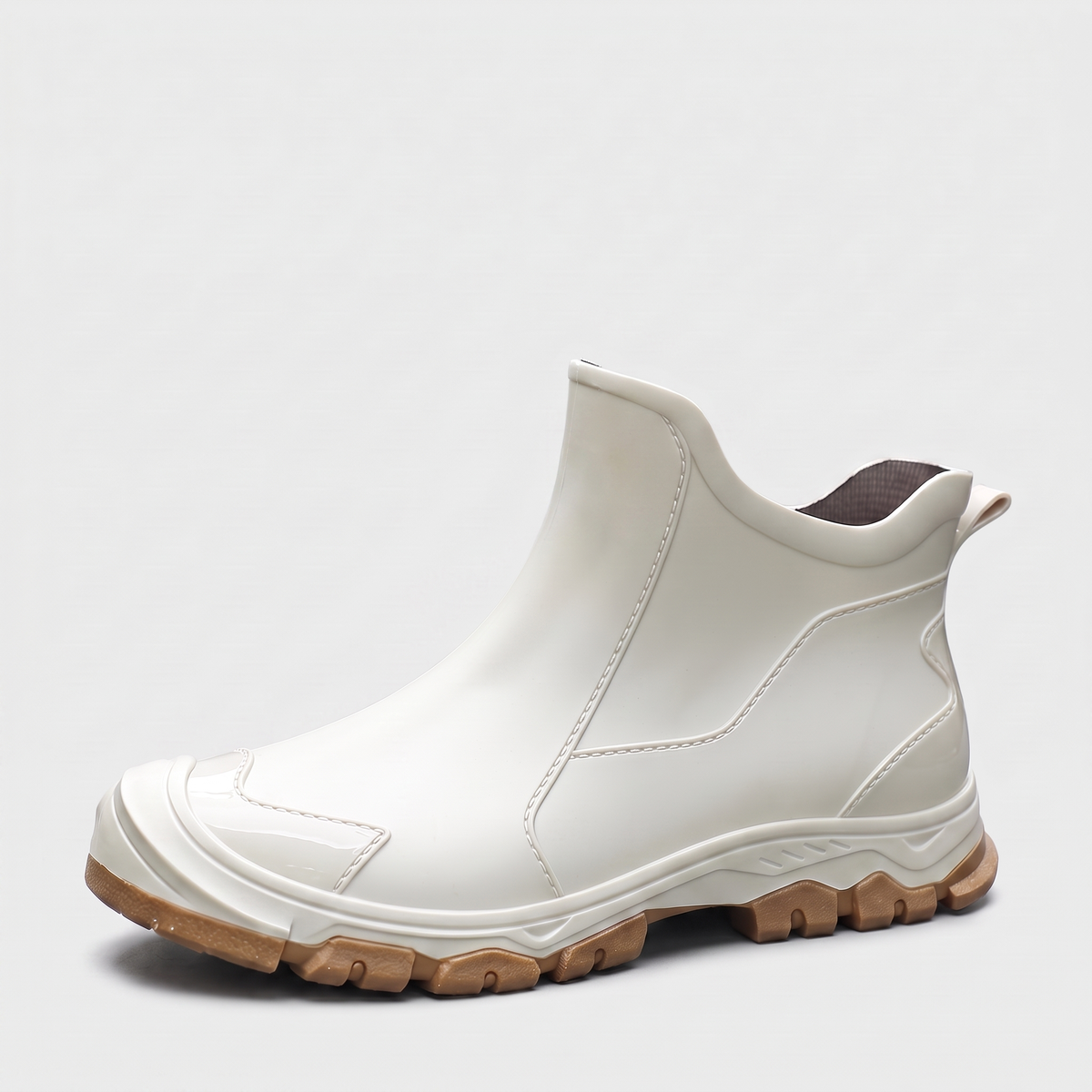 A single off white ankle rain boot with a brown tread sole, shown at a three quarter angle on a plain grey background.