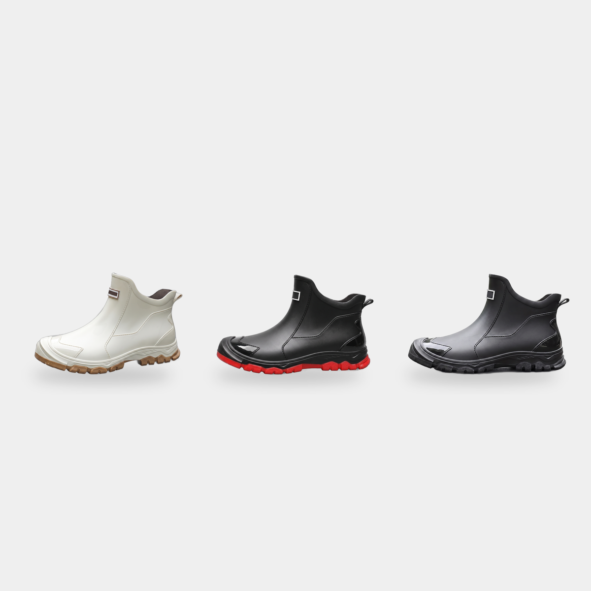 Three ankle rain boots in off-white, black with red sole, and all black, shown in profile view.