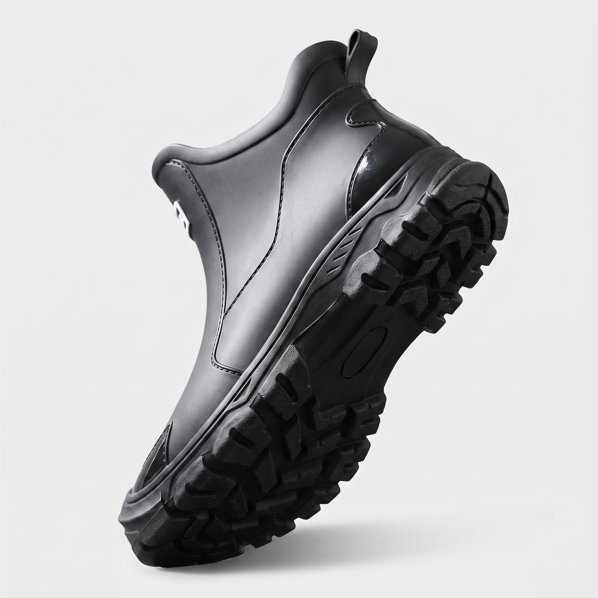 A black chunky-soled ankle rain boot shown at an angle highlighting the tread sole.