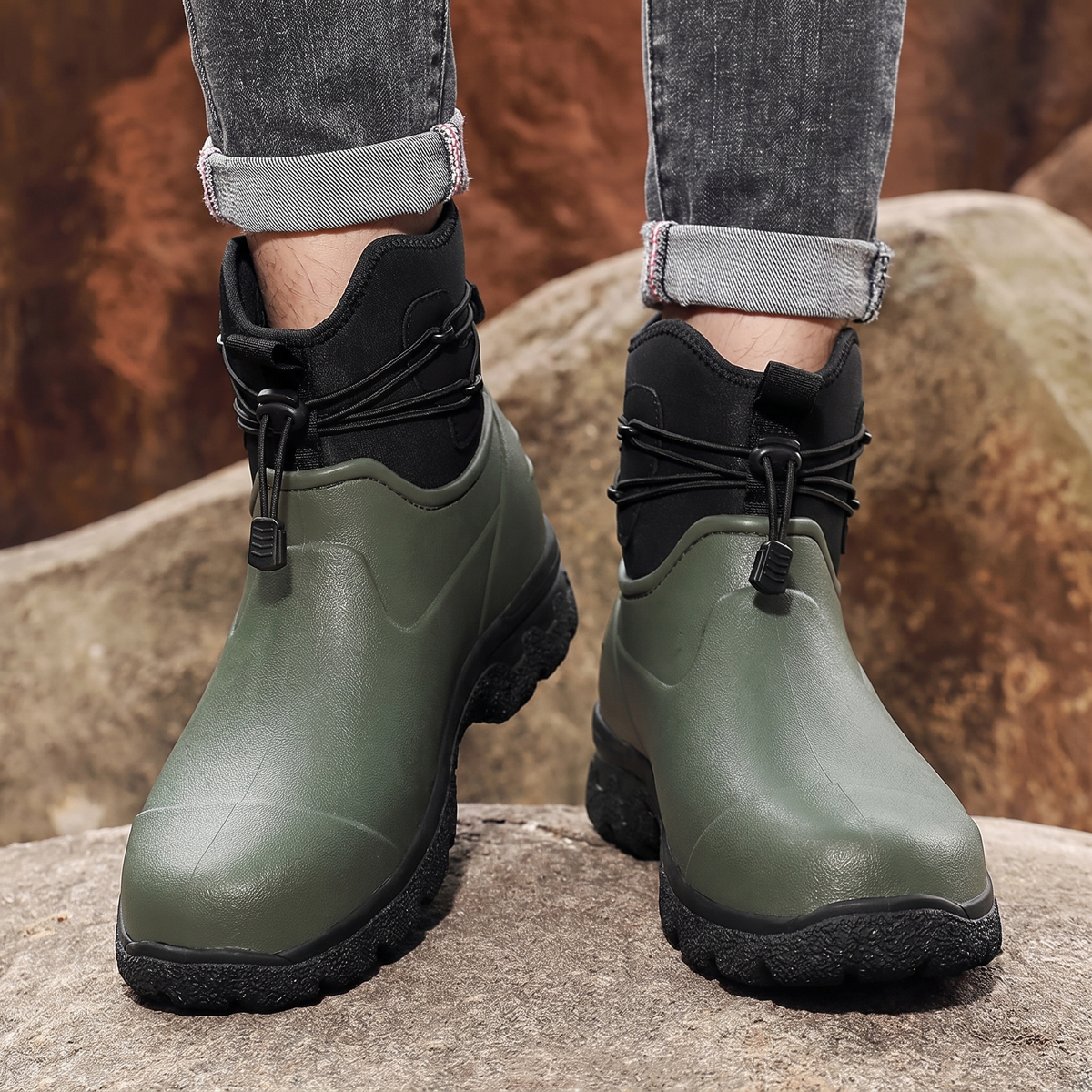 Groene en zwarte regenlaarzen met veterdetail, gedragen door een persoon op rotsen | Boutique Moda