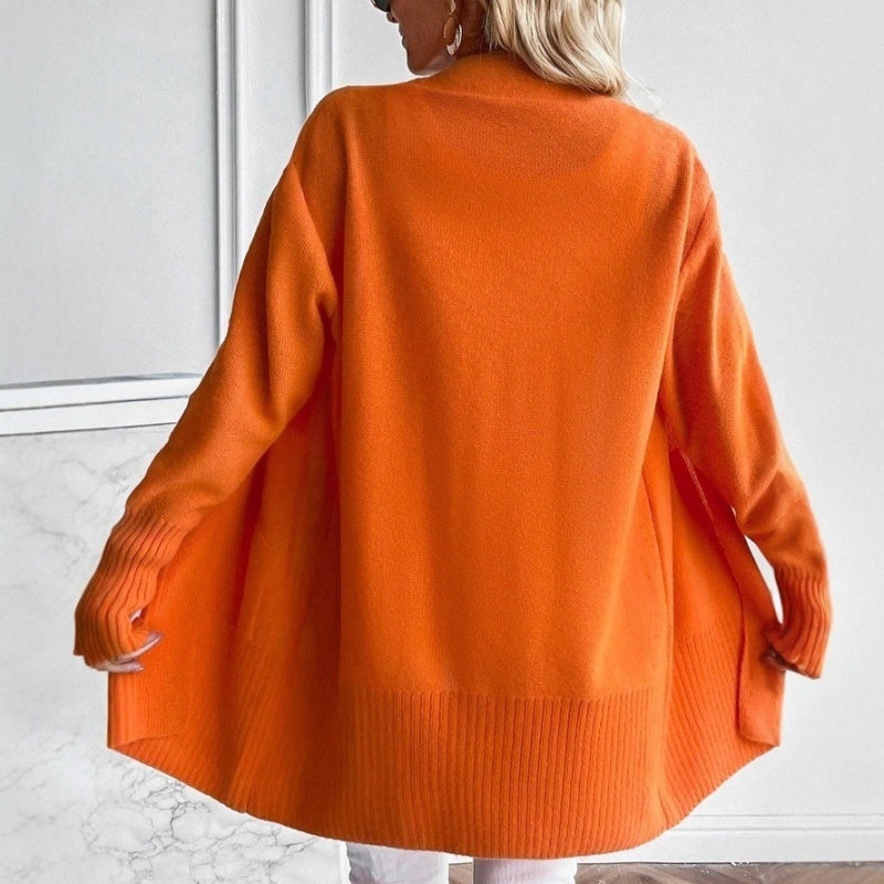 A woman seen from behind wearing an oversized orange ribbed-cuff cardigan with white pants.