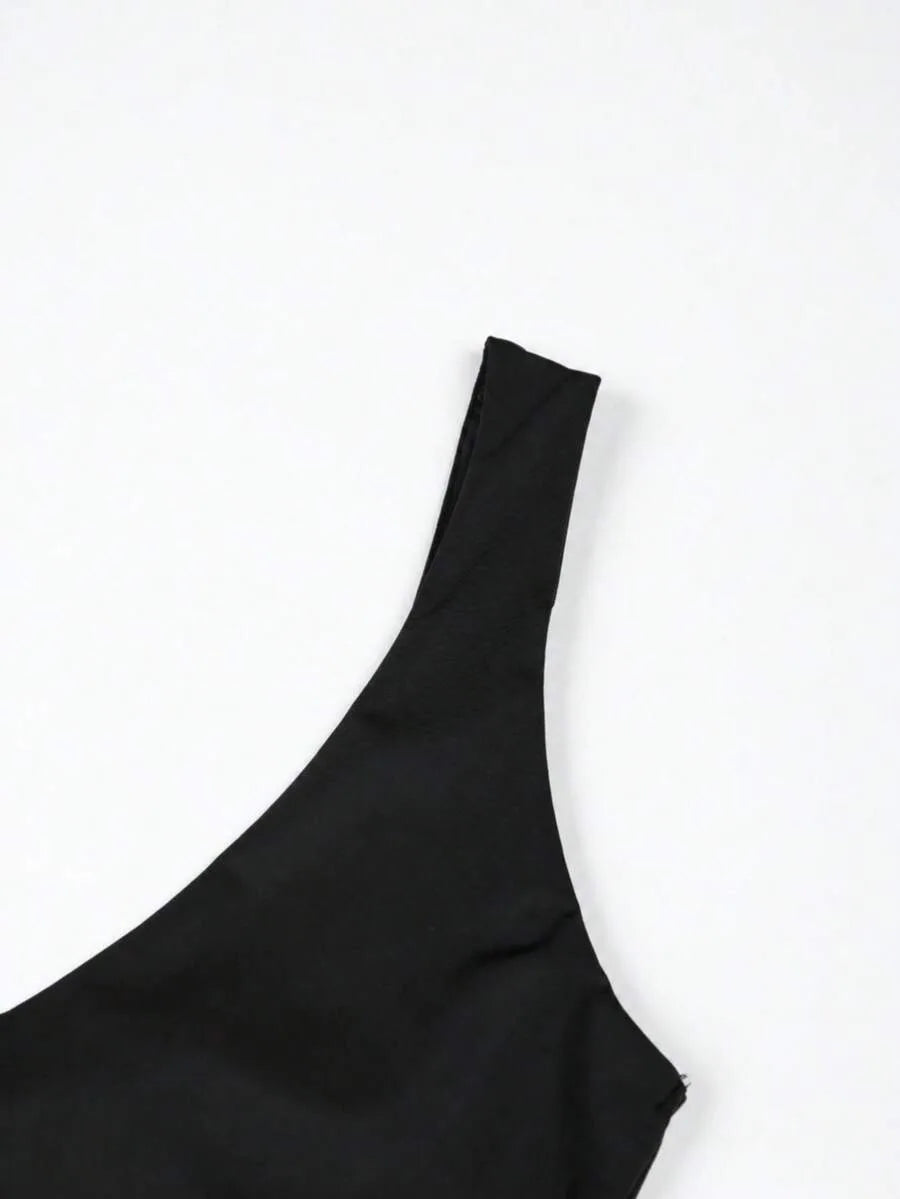 Close up of a black bodysuit shoulder strap and neckline against a white background.
