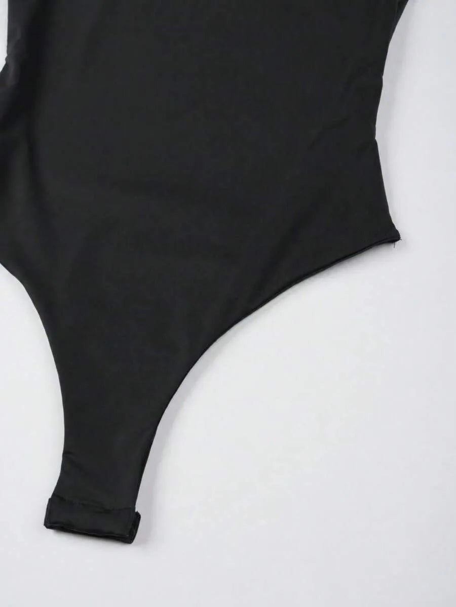 Close-up of a black bodysuit garment laid flat showing the crotch and side seam area with a small fabric tab.