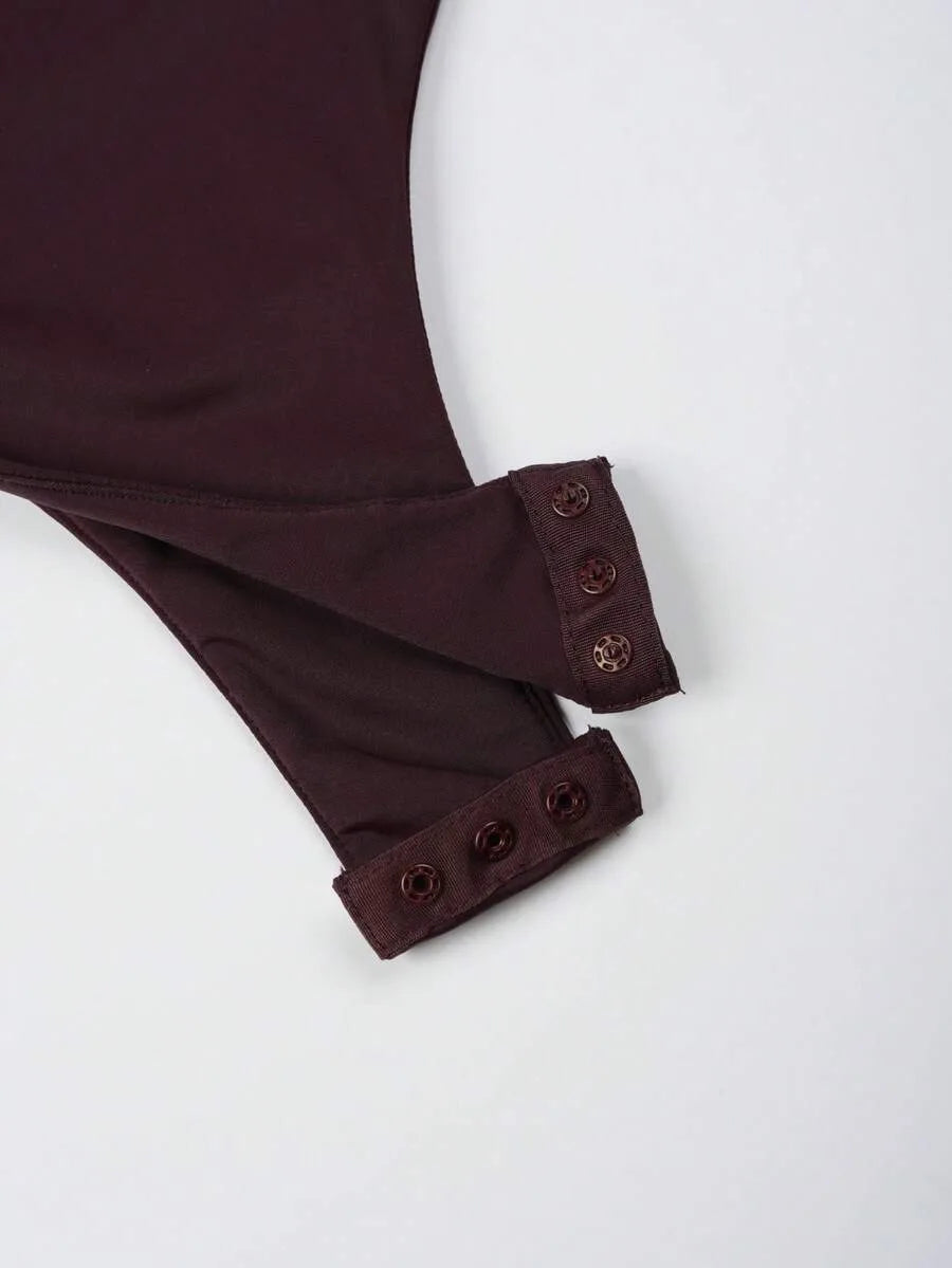 Close-up of a dark maroon bodysuit fabric showing the crotch area with two snap button closures.
