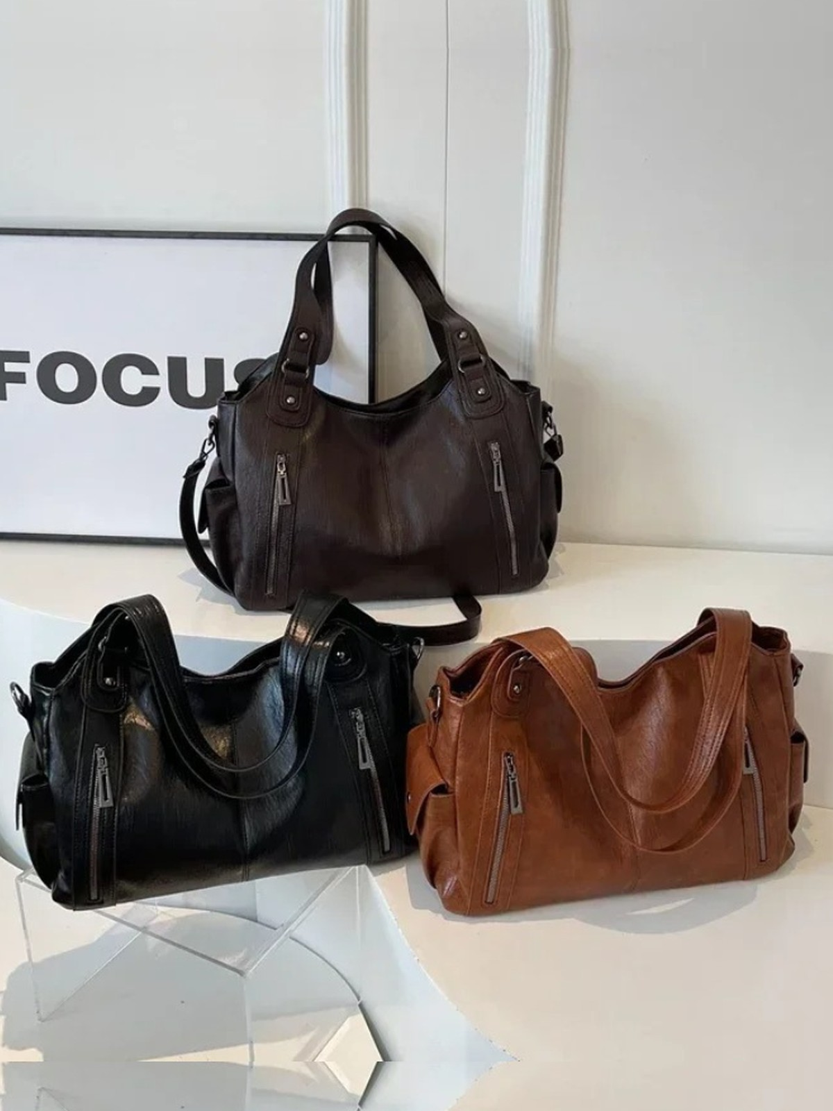 Drie leren schoudertassen in bruin, zwart en cognac, uitgestald | Boutique Moda
