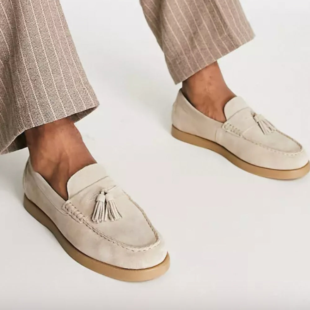 Beige suède loafers met kwastjes, gedragen aan voeten met beige broek | Boutique Moda
