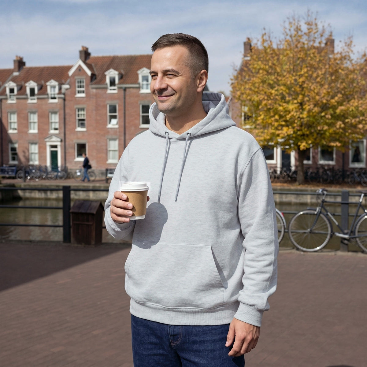 Man draagt grijze oversized fleece hoodie met capuchon en buidelzak aan een gracht in Utrecht | Boutique Moda