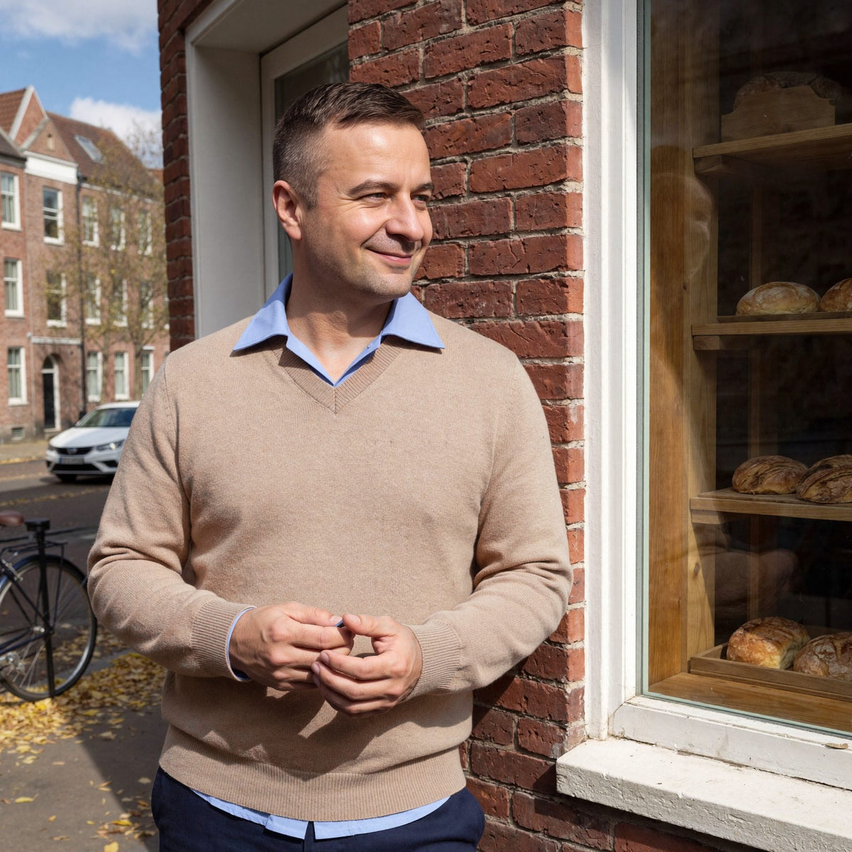 Man draagt de beige kasjmier trui met V-hals over een lichtblauw overhemd bij een bakkerij in Utrecht | Boutique Moda