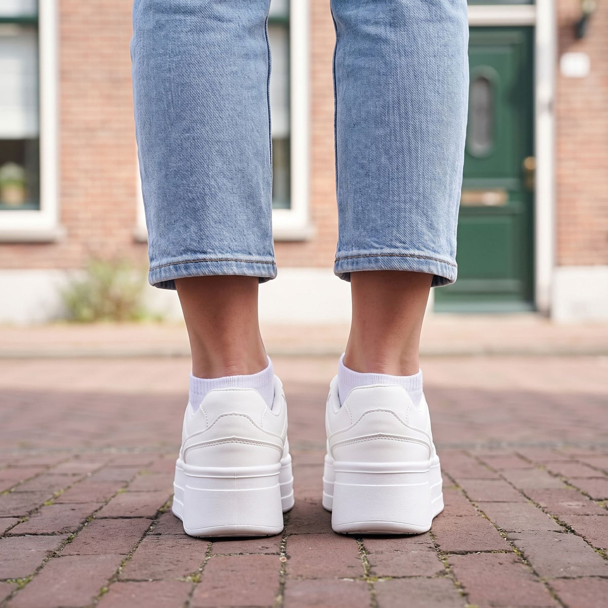 Witte plateau sneakers dames van achteren gezien, effen witte hiel en dikke plateauzool, gedragen met cropped jeans | Boutique Moda