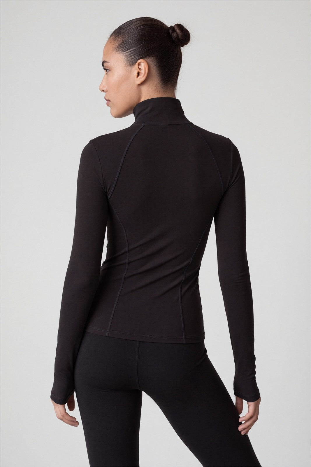 Achterkant van het zwarte sportvest met opstaande kraag en duimgaten, gedragen door vrouw met zwarte legging | Boutique Moda