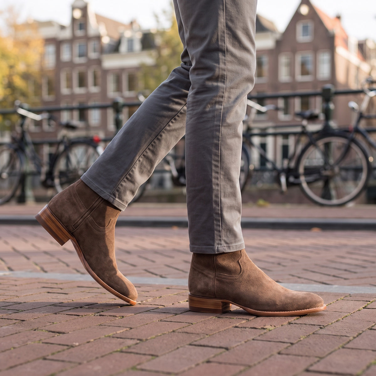 Bruine suède enkellaarzen met rits, gedragen met een grijze chino langs een Amsterdamse gracht | Boutique Moda