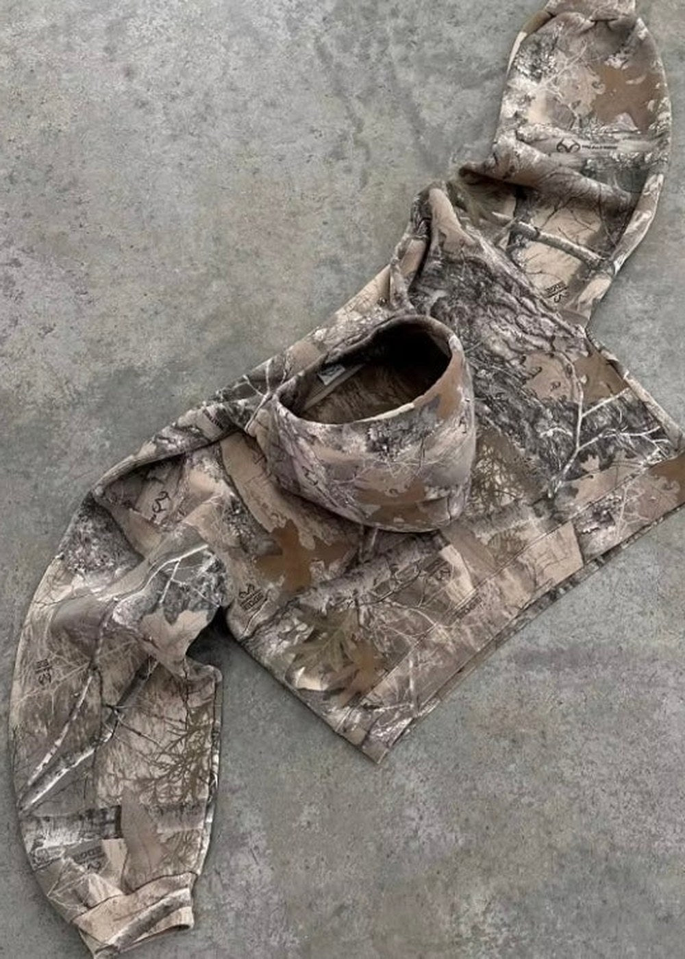Camouflage hoodie met capuchon, plat neergelegd op betonnen ondergrond | Boutique Moda