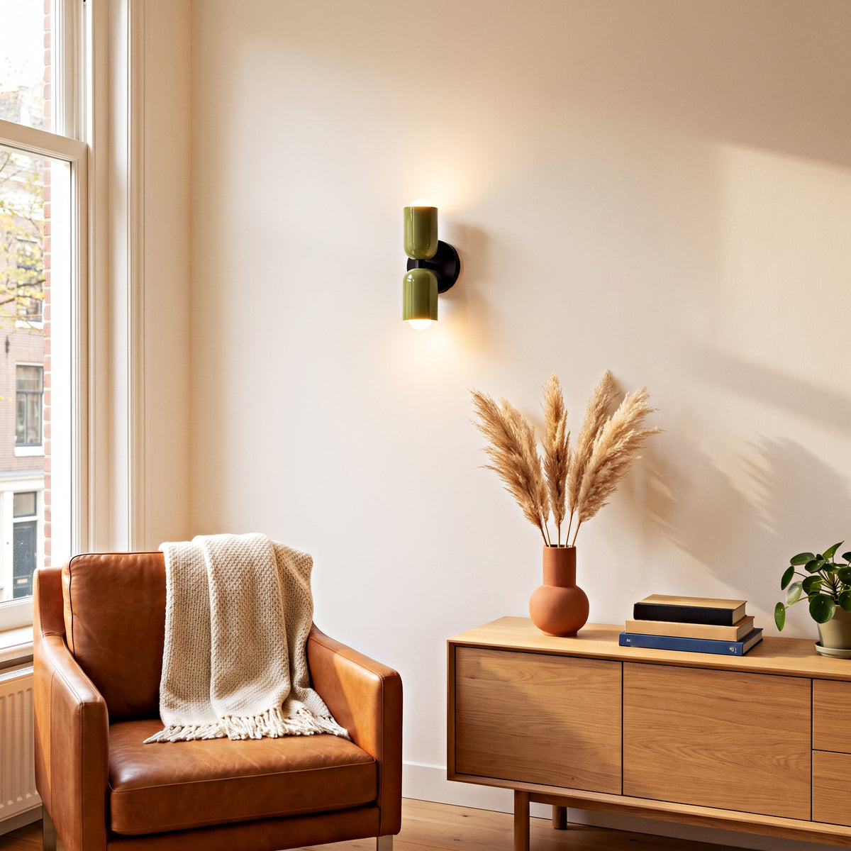 Groene dubbele wandlamp brandend aan de muur in een lichte woonkamer, licht schijnt omhoog en omlaag | Boutique Moda